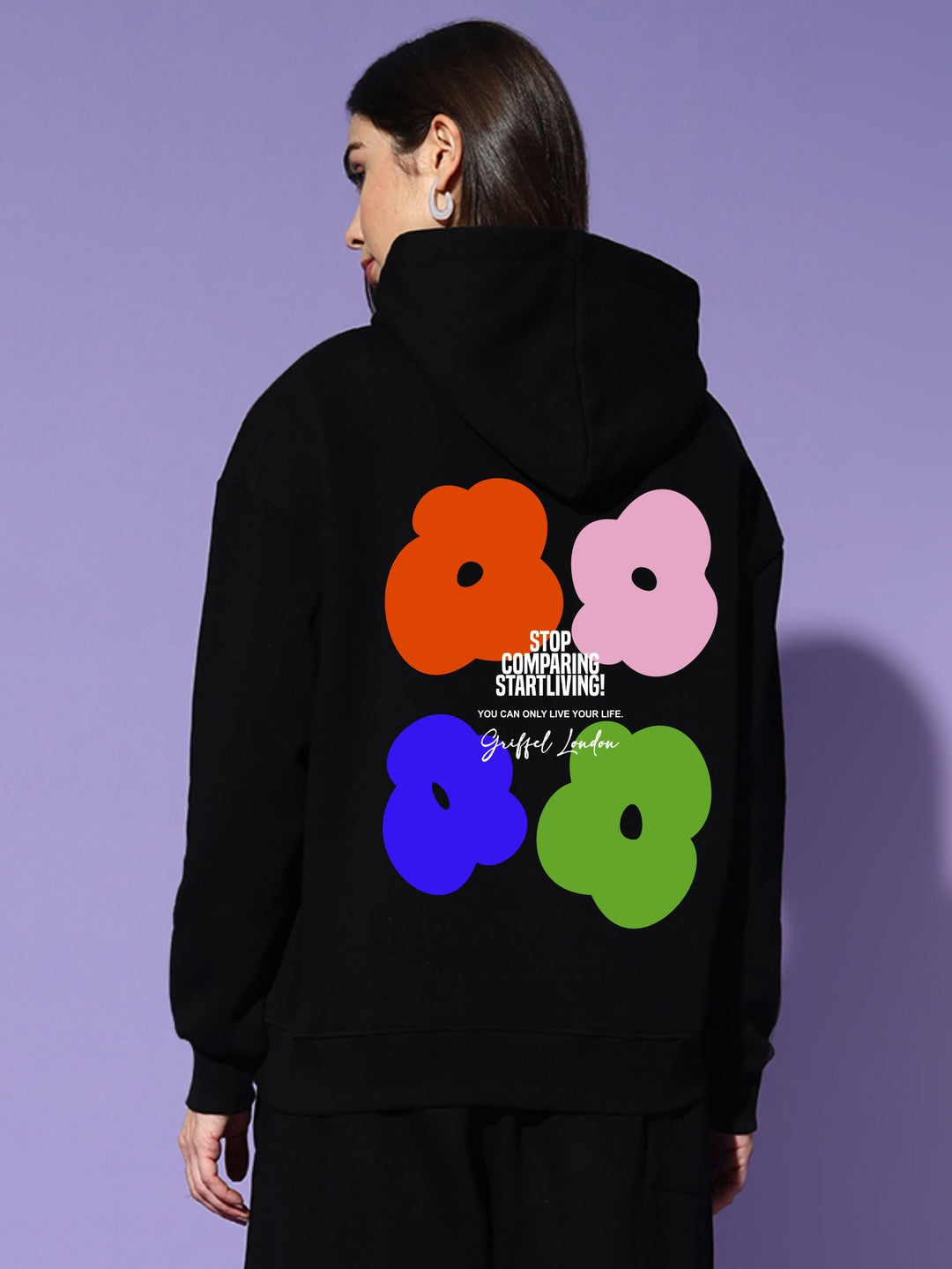 Person wearing a black hoodie with colorful floral design on a purple background