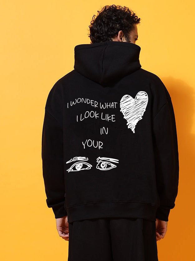 Person wearing a black hoodie with text and graphics on the back against an orange background