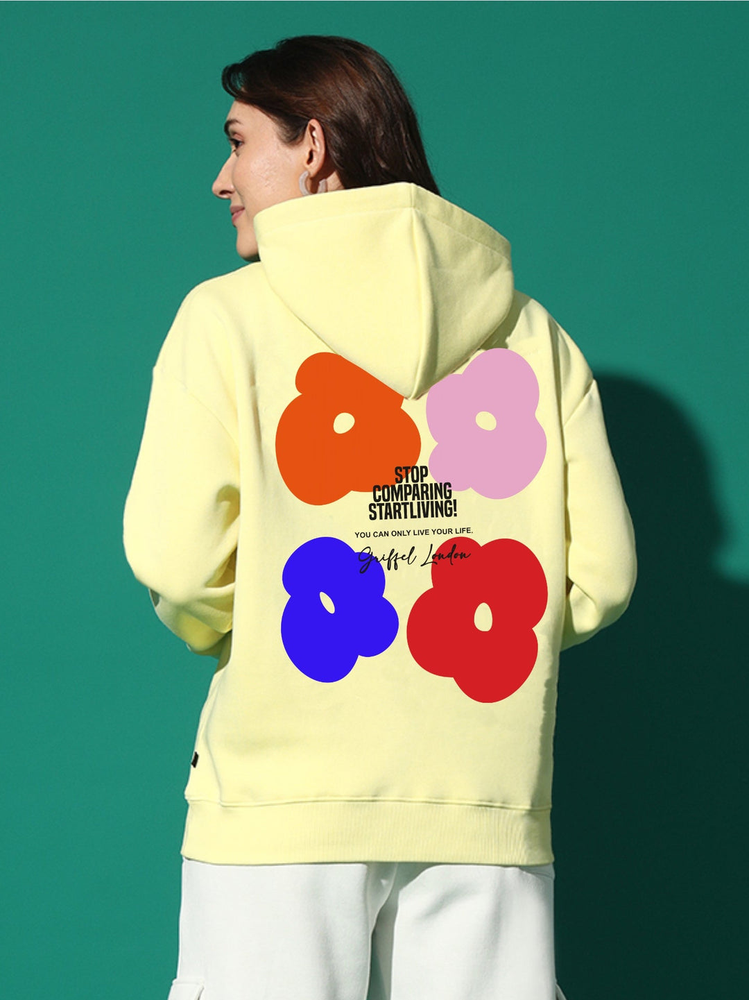 Person wearing a light yellow hoodie with colorful flower designs on the back against a green background